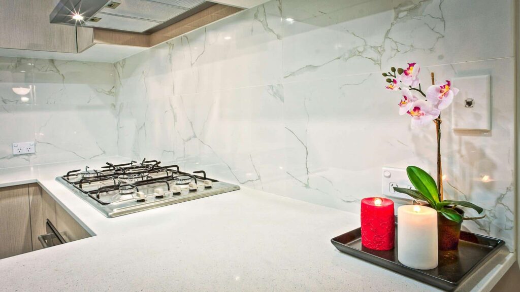 Modern kitchen with a built-in gas cooktop, marble backsplash, and decorative candles with an orchid flower.