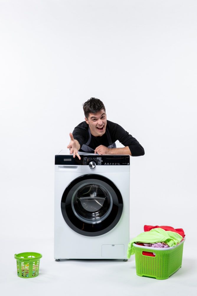 Man smiling beside a front-load washing machine with laundry baskets